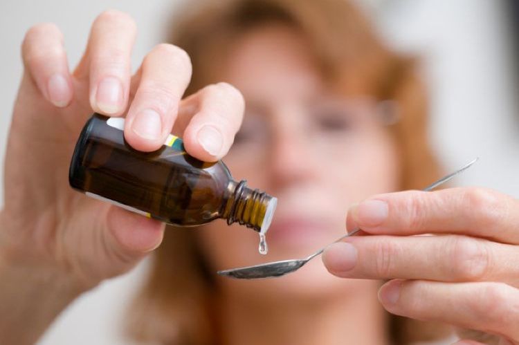 Une femme verse du médicament goutte à goutte dans une cuillère