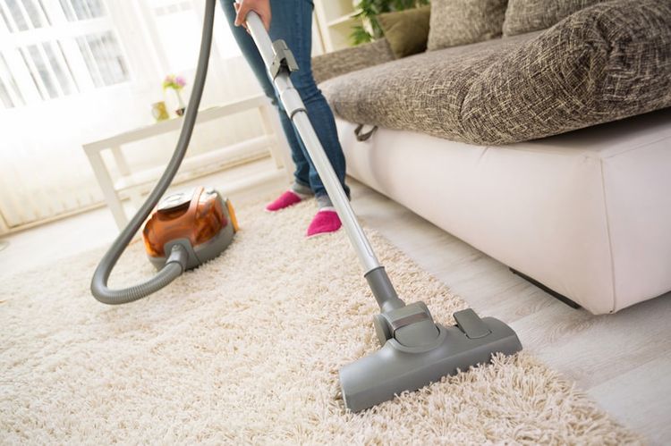 Une fille passe l'aspirateur sur un tapis