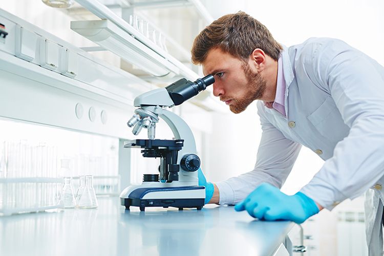 Un technicien de laboratoire devant un microscope